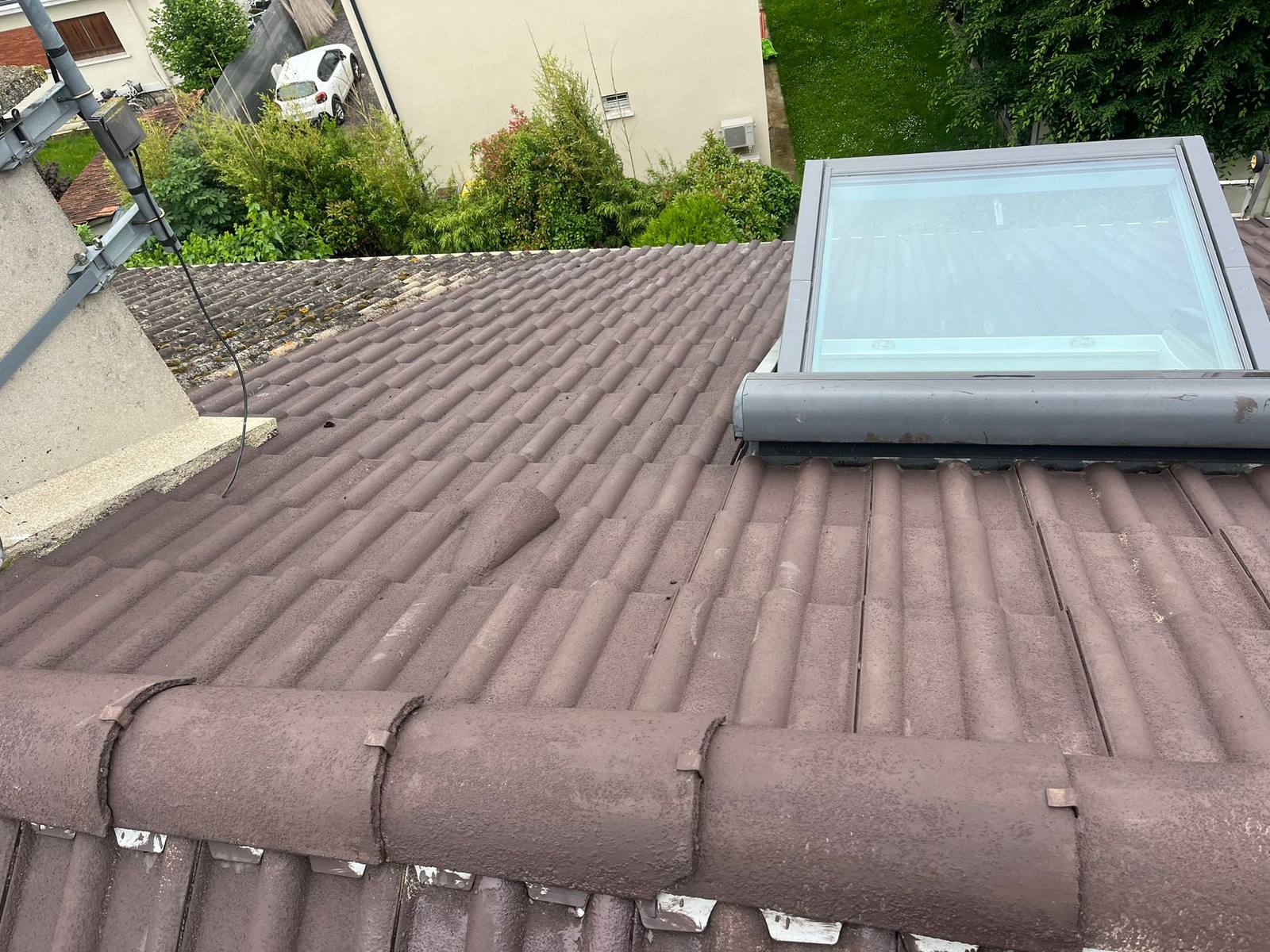 Pose d'une fenêtre de toit Velux sur une toiture en tuiles.