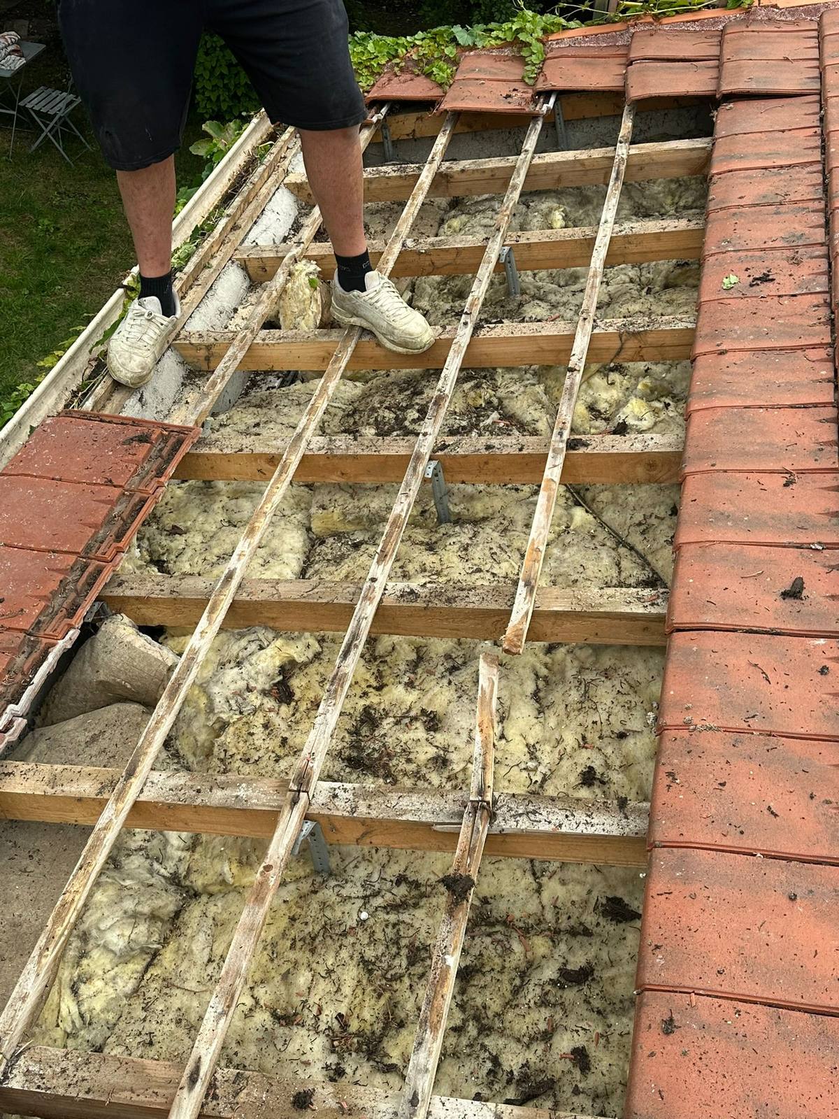 Réfection de la structure d'une toiture le long d'un mur de brique.